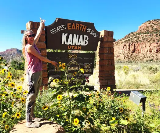 lady standing with arms spread by a Kanab Utah sign