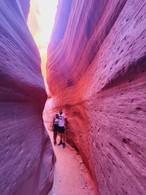 couple standing together in a red glow in a slot canyon in Kanab
