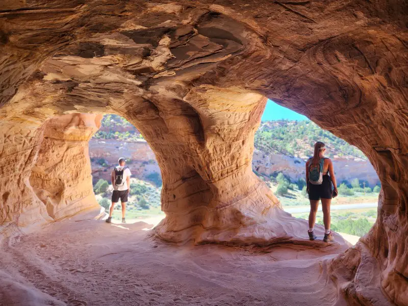2 people each looking out an overlook in a cave