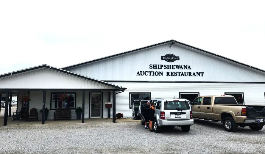 white building of Auction Restaurant in Shipshewana with 2 cars in front of it