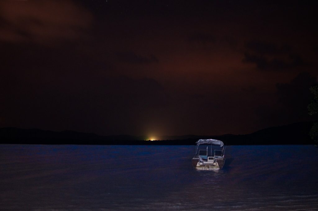 boat in dark water in front of the setting sun