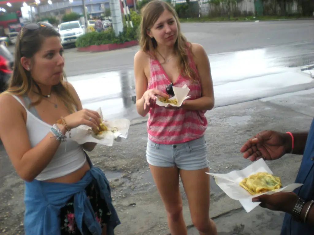 2 girls Eating Doubles street food in trinidad