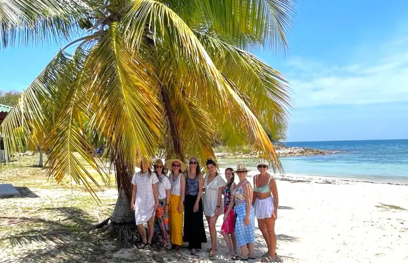 group of ladies standing under a palm tree on a beach i n Vieques