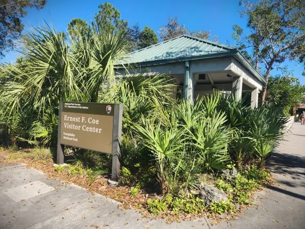 Ernest F Coe Visitor Center sign in front of the poles of a building in Everglades National Park