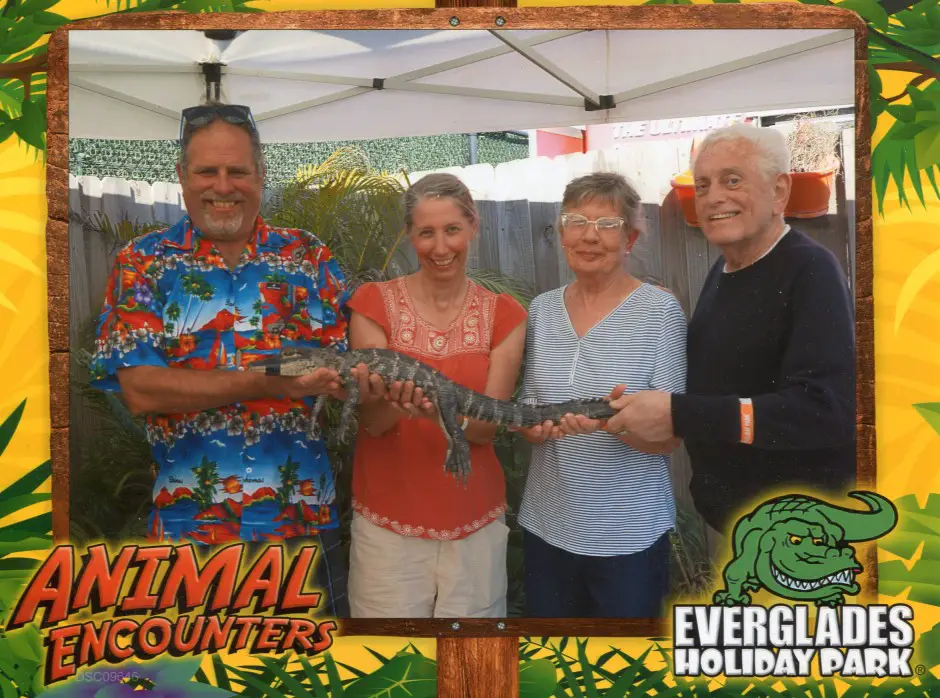 4 people holding a small alligator