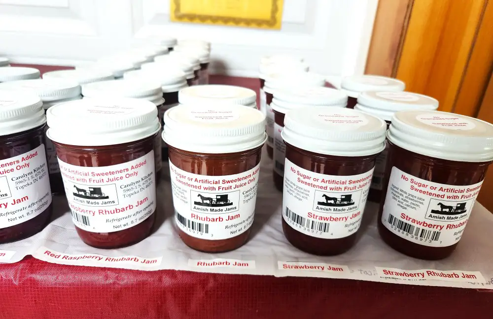 jars of jam on a table in a line and sorted by flavor