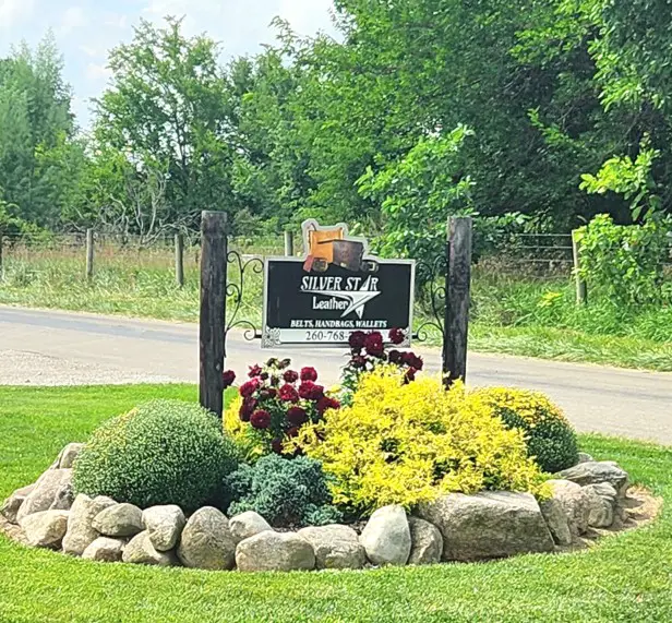 black sign for SilverStar Leather Goods in a flower garden in Amish Country