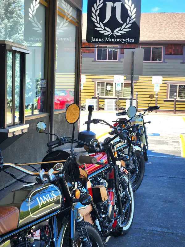 row of motorcycles outside on pavement beneath a Janus motorcycle sign
