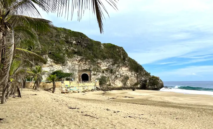 Sandy beach with a tunnel through a mountain in the distance in Puerto Rico