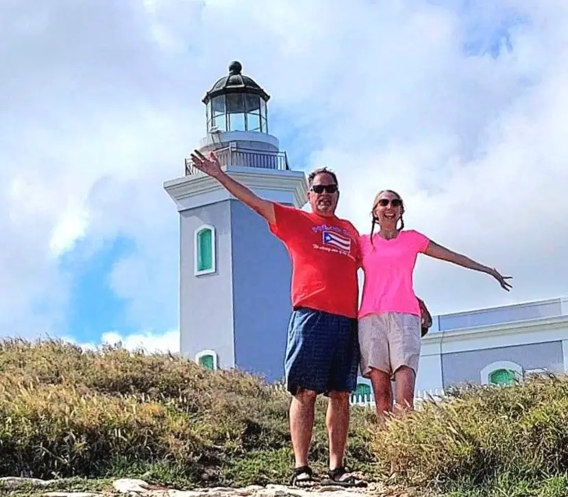 man and woman with outstretched arm in from of a lighthouse tower in Puerto Rico