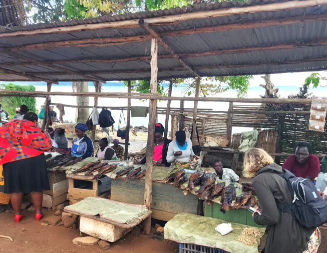 people selling fish under a metal awning