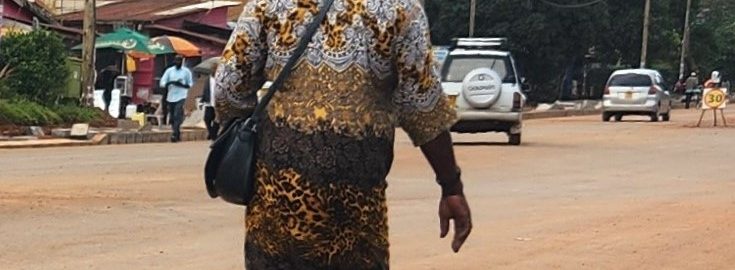 person carrying big white bag on head and walking down a dirt road