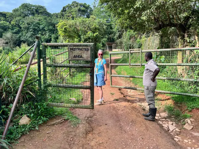 woman standing behind am open gate that says Restricted Entry with a tour guide ranger next to her