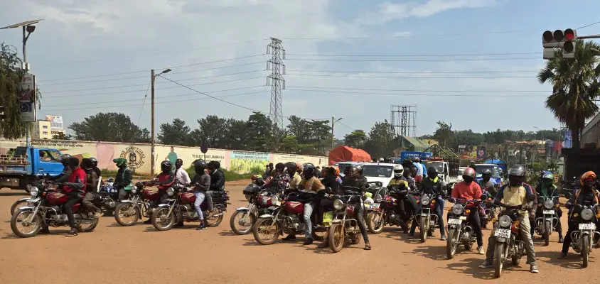 lots of motobikes in a dirt road traveling in Uganda