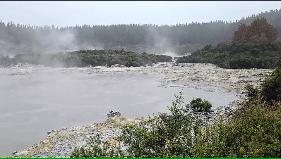 large lake with steam coming off of it in Rotorua New Zealand