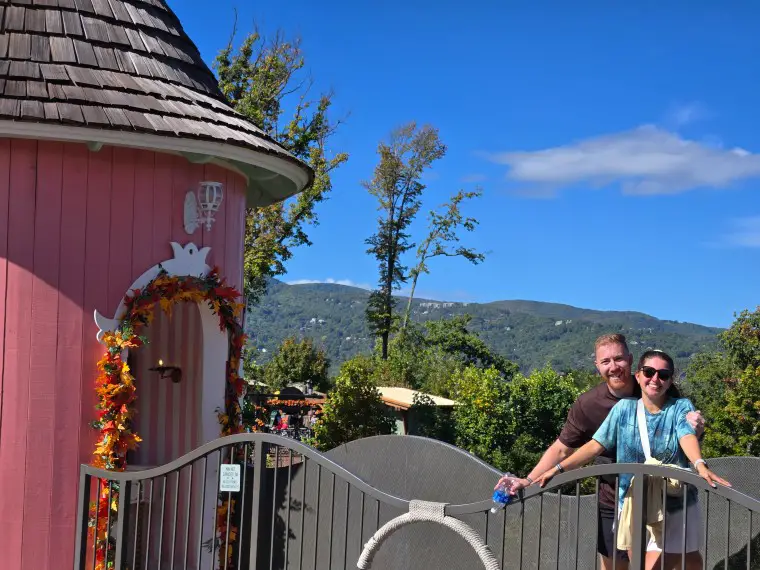 couple on a walkway in front of the mountains and next to a pink hut