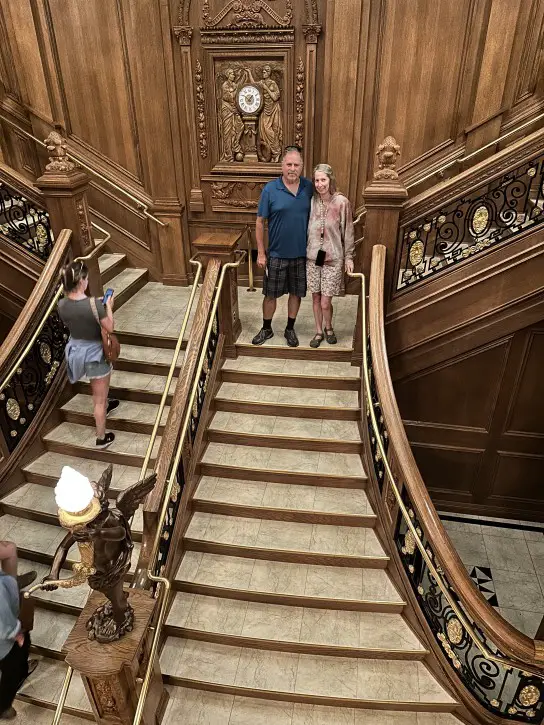 man and woman posing on a gold staircase replica from the Titanic