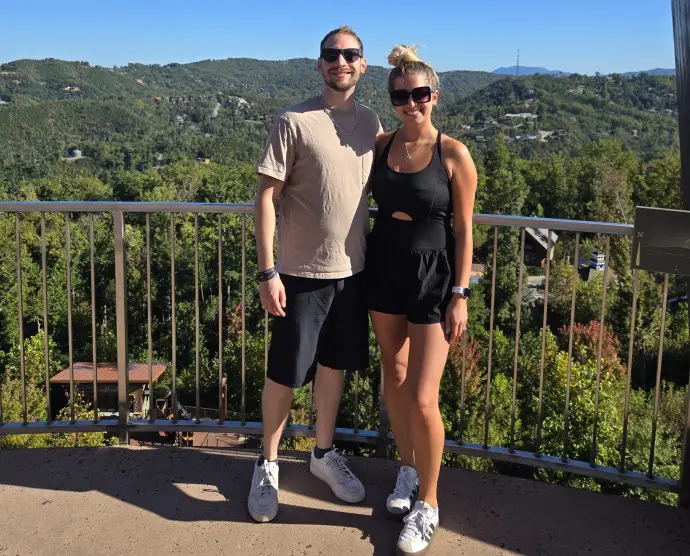 couple standing in front of a rail at the top of an observation platform overlooking the Smoky Mountains in Gatlinburg