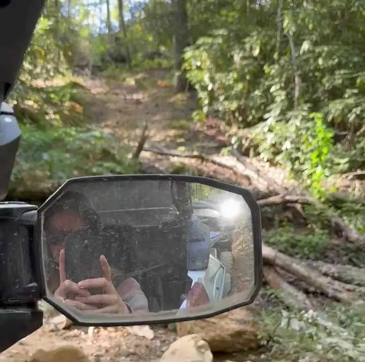 person looking into mirror and taking a photo of the trees in the mountain scenery