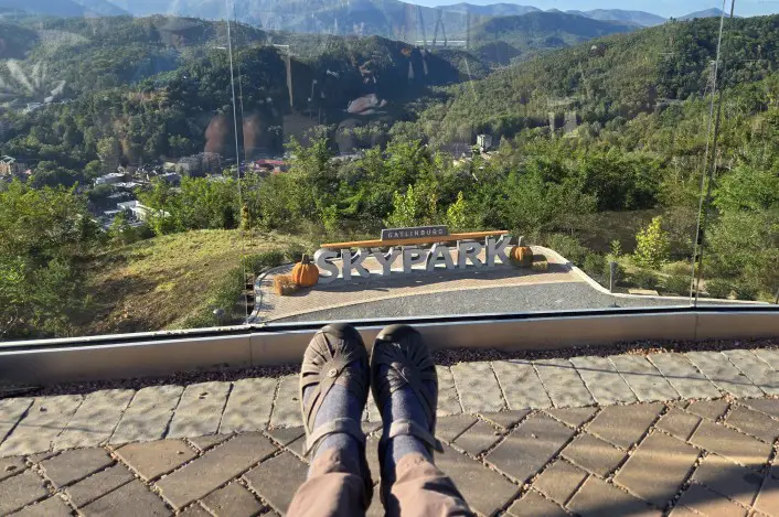 2 legs outstretched in front of a beautiful mountain view and the Skypark sign